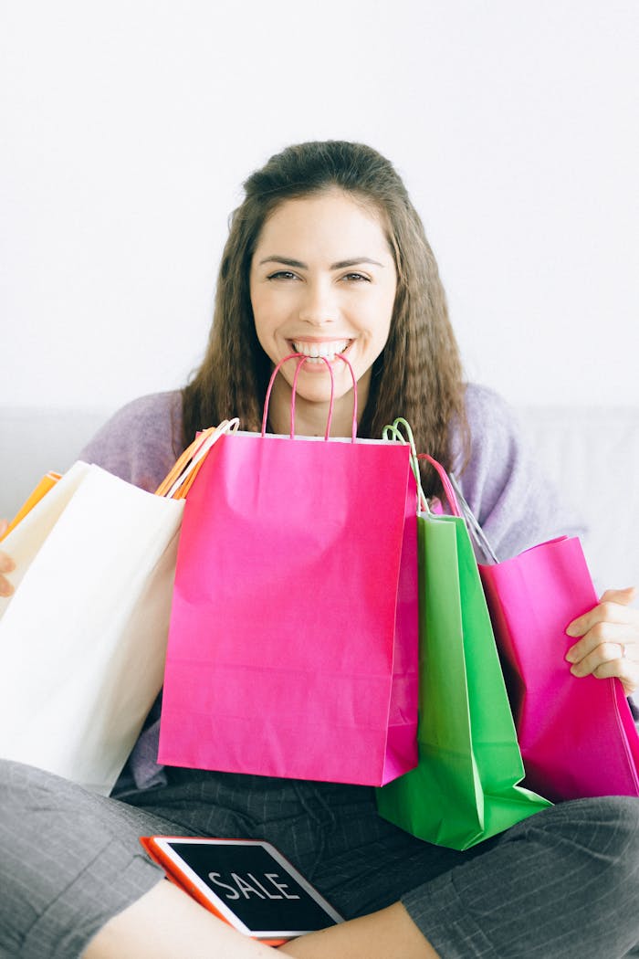 Happy woman sitting with vibrant shopping bags, enjoying a sale.
